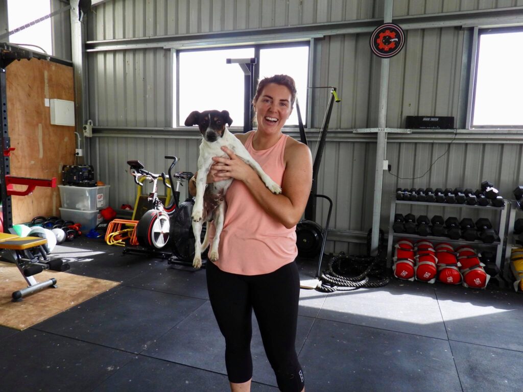 Hannah holding her dog in her gym