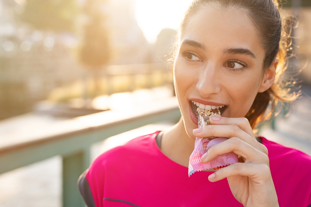 Athletic,Woman,Eating,A,Protein,Bar.,Closeup,Face,Of,Young